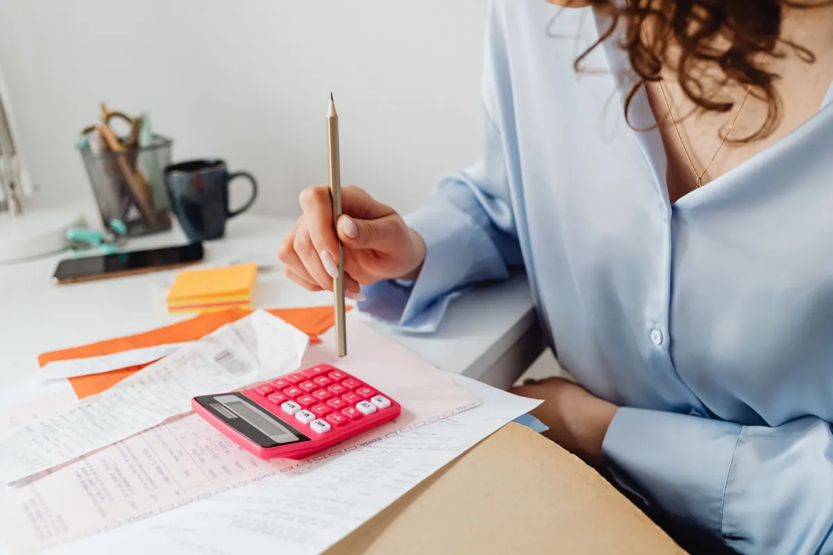 Contribuente che controlla moduli di pagamento e cartelle con la calcolatrice per pianificare le rate della rottamazione